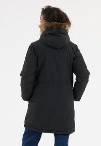 Zwarte pufferjas met een faux fur-voering in de capuchon, met een gemiddelde lengte en lange mouwen. Glad oppervlak, minimalistisch ontwerp.