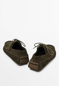 Scarpe in suede marrone con lacci, caratterizzate da una forma rotonda, una consistenza morbida e dettagli in gomma sul tallone posteriore per maggiore stabilità.