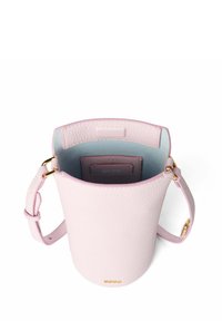 Rund rosa läderhandväska med slät textur, som har ett ljusblått innerfoder, guldhardware och en justerbar rem.