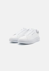 Zapatillas blancas con parte superior de cuero suave, puntera redonda y suela de goma tonal. Cuenta con un talón con patrón y cordones planos.