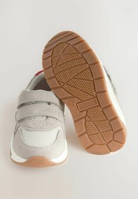 Grå mocka och mesh sneakers med kardborreband. Vit mellansula och texturerad gummisula. Höjd häl för stabilitet, röd accentdetalj.