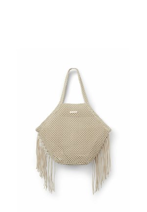 Beżowa pleciona torba typu tote z siatki z frędzlami po bokach i pojedynczym paskiem do noszenia.