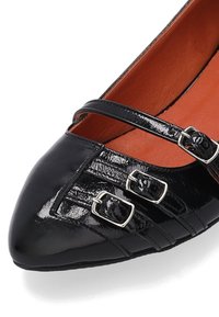 Czarne lakierowane baleriny z zaostrzonym noskiem, z dwoma regulowanymi paskami i srebrnymi klamrami, oraz teksturowanym wzorem po bokach.