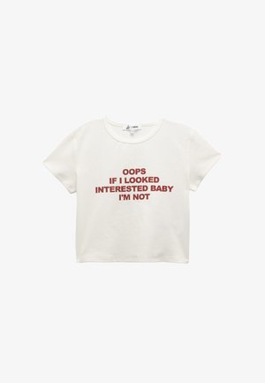 Witte crop top gemaakt van katoen. Bevat rode tekst: "OOPS ALS IK GEÏNTERESSEERD LIJKTE, EEN BABY BEN IK NIET." Korte mouwen en ronde halslijn.