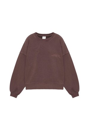 Brązowa bluza z okrągłym dekoltem, długimi rękawami i ściągaczami, z małym napisem "DESIGNED FOR CHANGE" na lewej piersi.