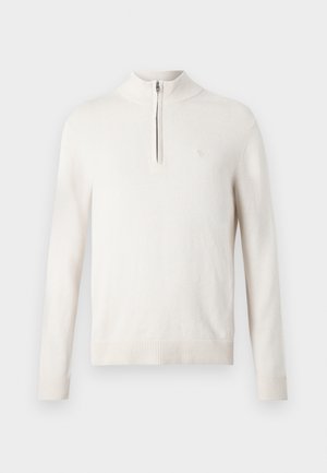 Világos bézs pulóver, félcipzárral a nyaknál, bordás mandzsettákkal és szegéllyel, puha anyagból készült, kis logóval a mellrészen.