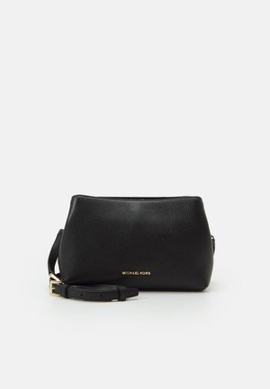 Czarna torebka Michael Kors na ramię z tłoczonej skóry z regulowanym paskiem i złotym logo na przodzie na białym tle.