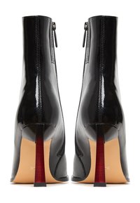 Zwarte gepatineerde leren enkellaarsjes met een strak ontwerp, hoge stilettohakken met rode accenten en een zijrits. Soepele textuur.