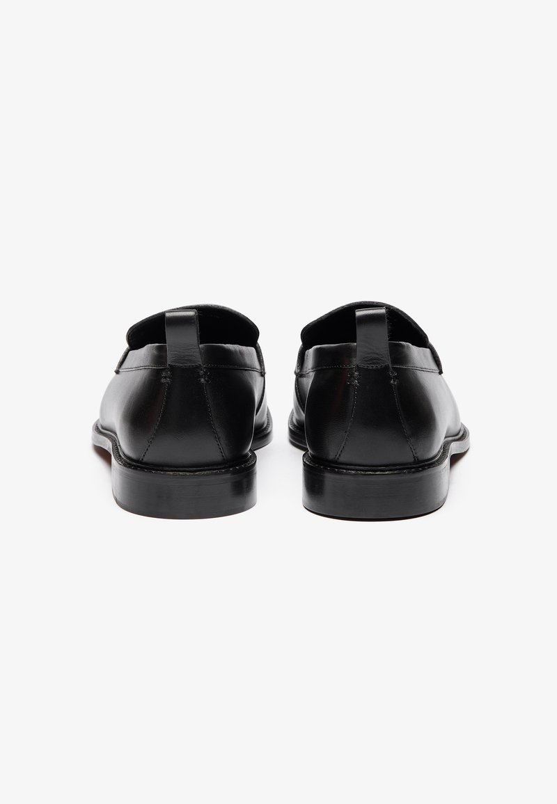 Scarpe in pelle nera con una superficie liscia, punta rotonda, linguetta sul retro e tacco basso a zeppa. Progettate per un aspetto classico.