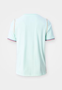 Ανοιχτό μπλε κοντομάνικο πουκάμισο με κόκκινο, λευκό και μπλε τελείωμα στα μανίκια και πορτοκαλί περιμετρική ραφή κατά μήκος των αρθρώσεων των ώμων, εμφανιζόμενο από πίσω.