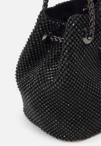 Borsa nera texture in materiale di perline, con chiusura a coulisse e dettagli in catena. Forma arrotondata con una finitura liscia.