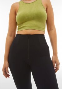 Top corto a coste verde con scollo rotondo abbinato a leggings neri a vita alta con dettagli con zip frontale.
