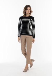 pulover cu dungi alb-negru, cu mâneci lungi, asociat cu pantaloni crem croiți și pantofi cu toc bloc crem; detaliu hardware minim.