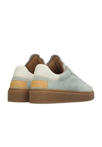 Zapatillas de ante azul claro con un talón de cuero blanco, acentos en tono marrón y una suela de goma texturizada en marrón. Presenta costuras visibles y marca.