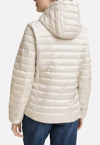 Lichtbeige donsjack met een capuchon, gekenmerkt door een doorgestikte textuur en een aansluitend ontwerp. Geribbelde manchetten en een gladde afwerking.