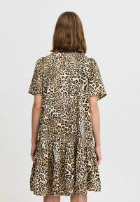 Šaty s leopardím potiskem, krátké rukávy, volánkový lem, vyrobené z lehkého materiálu. Vyznačují se béžovým a černým vzorem po celém povrchu.