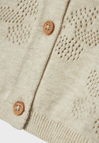 Cardigan beige lavorato a maglia con bottoni di legno, caratterizzato da un motivo testurizzato e orlo a coste. Tessuto morbido con dettagli di design a trama aperta.