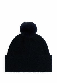 Marine blauwe gebreide muts met een gestructureerd weefsel, gekenmerkt door een grote, zachte pompon bovenop en een omgeslagen manchet aan de onderkant.