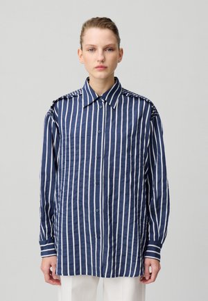 Chemise à rayures bleu marine et blanche à manches longues avec un boutonnage à l'avant, col classique et accents détaillés aux épaules. Texture de tissu lisse.