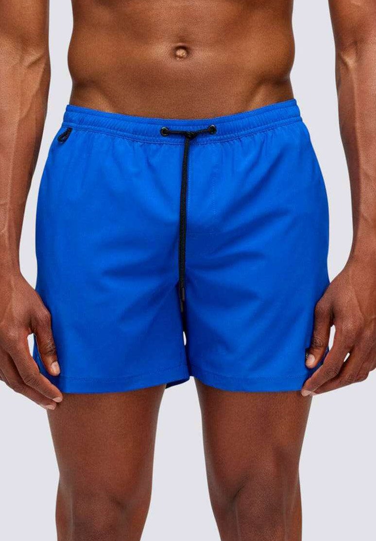 Pantaloni da nuoto blu realizzati in tessuto leggero, con una vita elastica e un cordoncino nero, caratterizzati da una texture morbida.