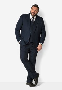 Marinblå tredelad kostym med en skräddarsydd blazer, matchande väst och byxor. Innehåller en vit skjorta och en mörk slips. Slät tygkvalitet och skräddarsydd passform.