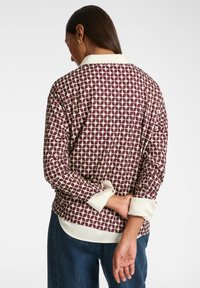Langärmlige Bluse mit einem bordeauxfarbenen geometrischen Muster auf einem cremefarbenen Hintergrund, kontrastierendem cremefarbenen Kragen und Manschetten sowie einem entspannten Schnitt.