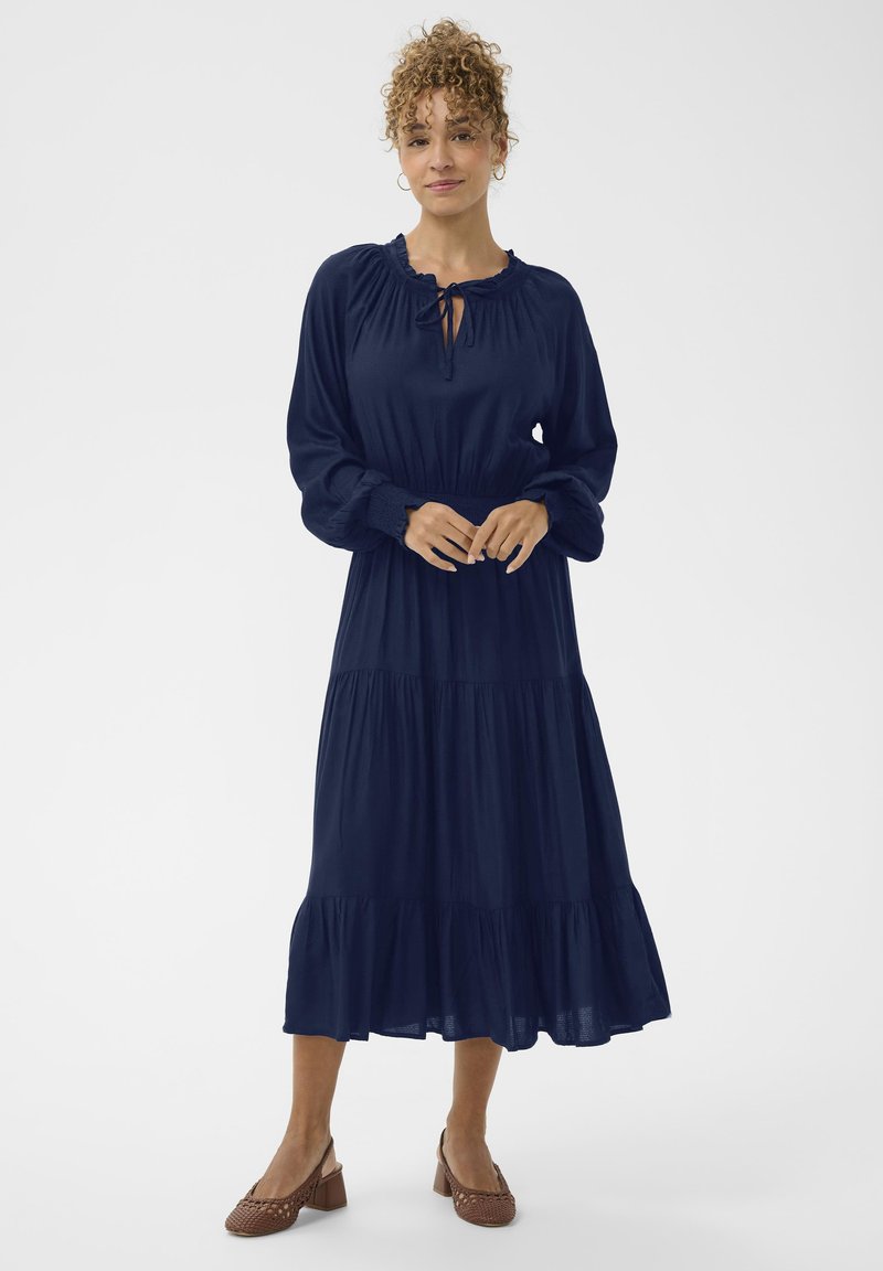 Tumši zilas krāsas garām piedurknēm kleita ar frēzētām apakšmalām un slāņiem. Mīksts audums ar brīvu piegriezumu, ar auklu pie kakla un elastīgām aprocēm.