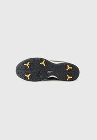 Talpa de pantof sport negru, cu vârfuri de tracțiune galbene, din cauciuc texturat și un design curbat, cu un logo imprimat.
