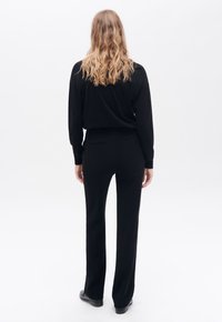 Zwarte lange mouwen top en recht model broek. Vloeiende stof, relaxte pasvorm. Minimalistisch ontwerp, geen zichtbare patronen of accenten.