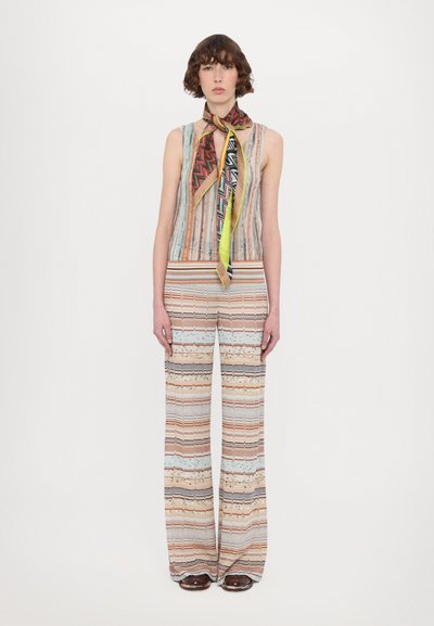 Pestrý pruhovaný outfit so topom bez rukávov a širokými nohavicami. Top má rebrovanú textúru; šál obsahuje geometrické vzory.