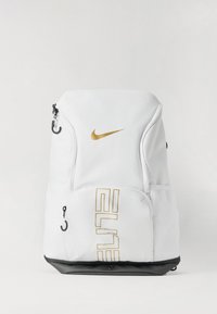 Biely batoh Nike so zlatým logom, má zipsové priehradky, čierne dno a sieťované bočné vrecká. Jednoduchý dizajn, funkčné detaily.