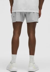 Ljust grå idrottsshorts i ett smidigt och lätt material, med en avslappnad passform. Vita sneakers med diskret branding och strumpor som går till mitten av vaden.