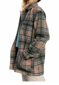 Chaqueta de cuadros en tono marrón, verde y azul. Confeccionada en tela suave, cuenta con un corte relajado, cierres de botones y bolsillos laterales. Presenta un collar.