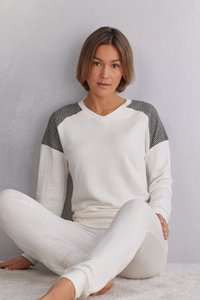Vitt ribbat loungedress set med en V-ringad långärmad topp som har mönstrade grå detaljer och bekväma, tajta byxor med elastiska muddar.
