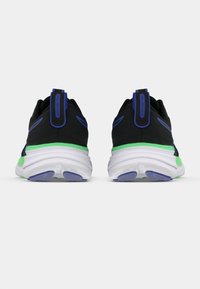 Chaussures de sport noires avec des accents bleus et un détail de talon vert. Elles présentent une tige texturée et une semelle blanche épaisse avec une bande de roulement en caoutchouc bleu.