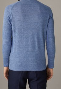 Pull bleu à manches longues en tissu tricoté avec une texture subtile, doté d'un col arrondi et d'une coupe décontractée.