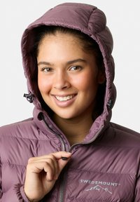 Lilla puffer-jakke med lynlås foran, justerbar hætte og et logo-accent. Struktureret stof med vandret quiltet mønster.