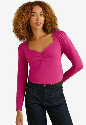 Long-sleeve bodysuit in vibrant pink, featuring a square neckline, subtle ruching at the front, and a form-fitting design. Paired with dark jeans.