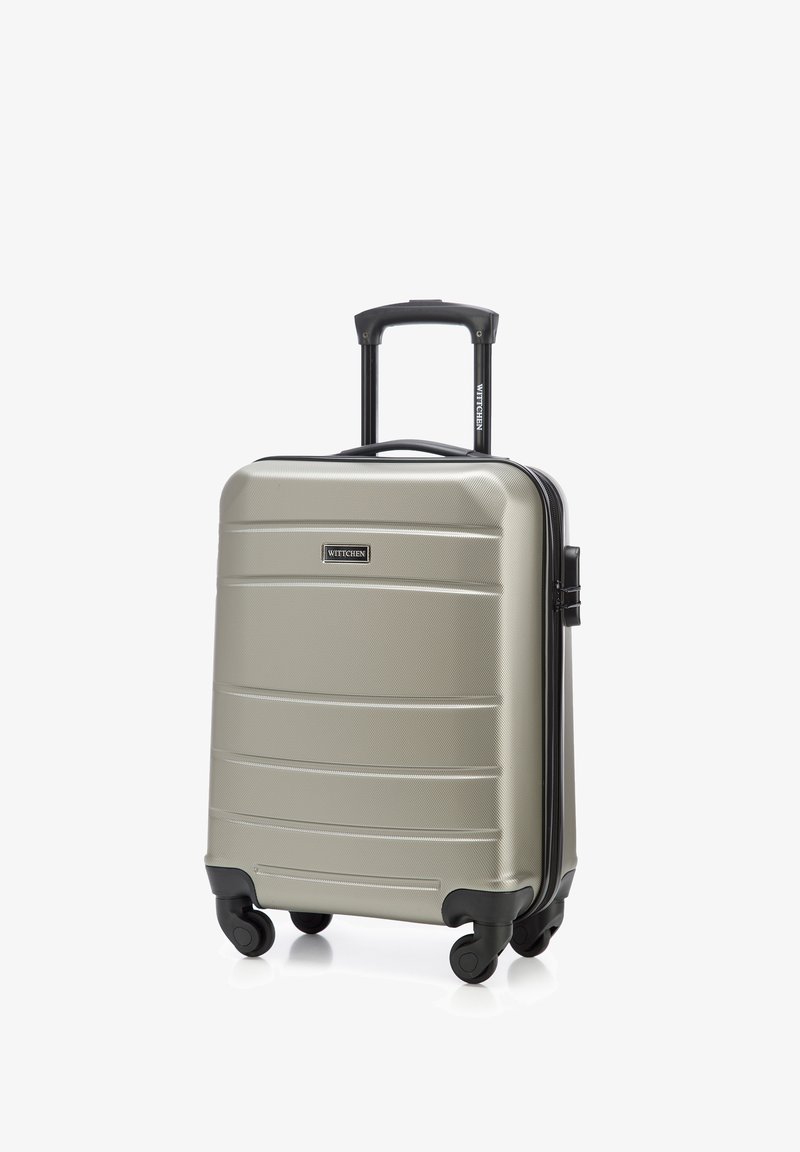 Valigia rigida argentata con superficie testurizzata, accenti neri, manico retrattile e quattro ruote per la mobilità. Presenta il logo del marchio sul davanti.