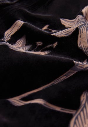 Juoda audinys su lygiu paviršiumi, puoštas šviesiai smėlio spalvos gėlių raštu. Dizainą sudaro pailgi žiedlapiai ir lenktos linijos.