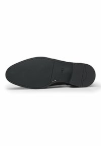 Suola di scarpa in pelle nera con superficie testurizzata, forma arrotondata e design piatto. Presenta il nome del marchio impresso e dettagli di cucitura.