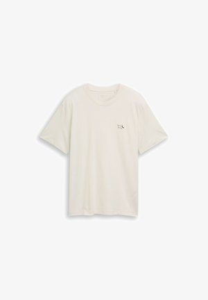 Kreemikas lühikeste varrukatega T-särk ümmarguse kaelusega, millel on vasakul rinnal väike must tekst "Spicy Ninny" ja tšillipipra pilt.