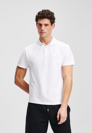 Witte katoenen polo shirt met een klassieke kraag, korte mouwen en een subtiele logo op de borst. Draagt bij donkere broek.