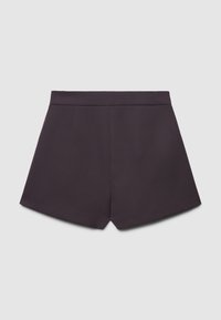 Pantaloni corti neri a vita alta, sartoriali, con una cintura larga e pieghe invertite sul davanti, su uno sfondo chiaro e semplice.