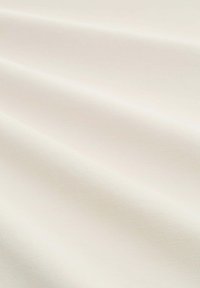 Helle beige Stoff mit glatter Textur, der feine diagonale Rippungen und einen sanften Fall aufweist, was sanfte Falten und Kurven erzeugt.