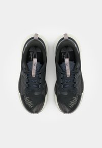 Baskets de sport noires avec une tige en mesh respirant, des accents texturés et une semelle de couleur claire. Les caractéristiques comprennent un col de cheville rembourré et des lacets.
