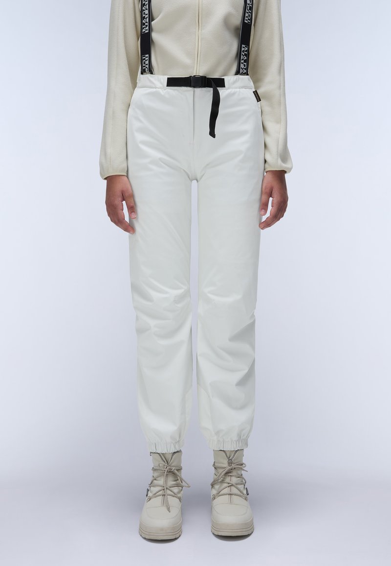 Witte waterdichte broek met elastische boorden en verstelbare zwarte tailleband. Gecombineerd met beige veterschoenen. Glad, glanzend textuur.