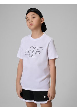 Chłopiec w białej koszulce 4F, czarnych szortach z logo 4F oraz czarnej czapce z daszkiem założonej do tyłu, stoi na szarym tle.