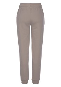 Jasno beżowe dresy wykonane z miękkiego materiału, z elastyczną talią, zwężanymi nogawkami oraz ściągaczami na kostkach.