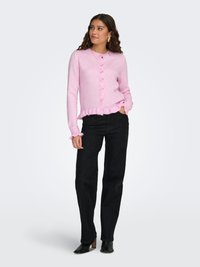 Light pink cardigan with a rounded neckline, button front, and ruffled hem. Black wide-leg pants and black heeled ankle boots.